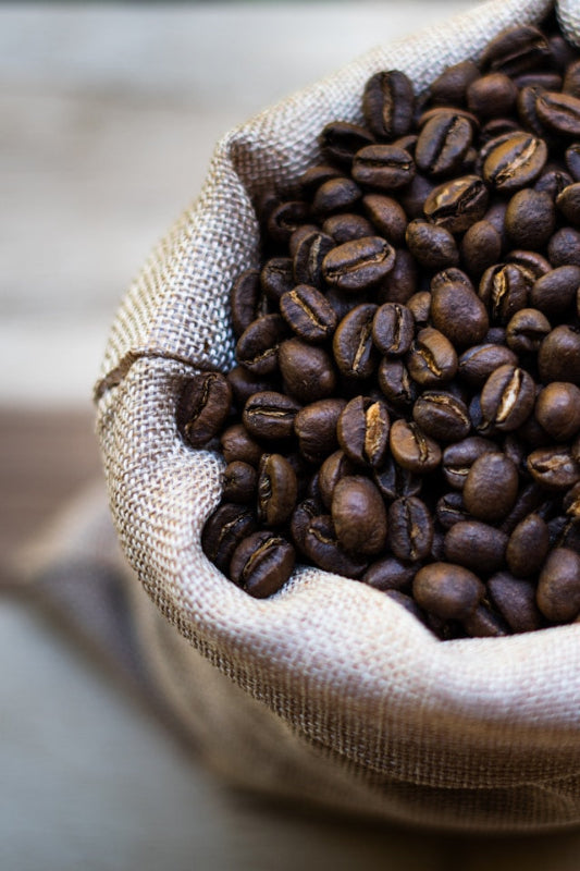 een zak single origin koffiebonen, omringd door een sfeer van ambacht en passie. De setting benadrukt de puurheid en transparantie van single origin koffie, waarbij elk detail vertelt over herkomst, vakmanschap en unieke smaakervaringen.